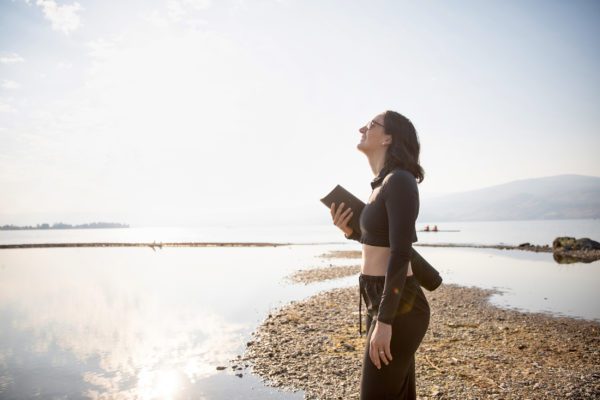 Woman on a sandbar at a lake wearing black UV protective clothing, the best colour to wear in the sun.
